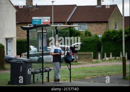 Eine Person mit einer Schutzhülle wartet an einer Bushaltestelle auf Bowhill Grove in Leicester, wo die örtlich begrenzte Sperrgrenze durchbricht. Nach einem Anstieg der Coronavirus-Fälle in der Stadt wurde eine lokale Sperre verhängt. Stockfoto