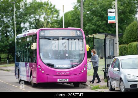 Eine Person, die eine Schutzwand trägt, fährt an Bord eines Busses auf Bowhill Grove in Leicester, wo die örtlich begrenzte Sperrgrenze durchbricht. Nach einem Anstieg der Coronavirus-Fälle in der Stadt wurde eine lokale Sperre verhängt. Stockfoto