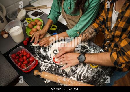 Nahaufnahme eines multiethnischen Paares, das in seiner Küche Kekse macht. Stockfoto