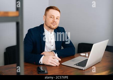 Der junge Geschäftsmann mit Modeanzug trägt Desinfektionsmittel Stockfoto