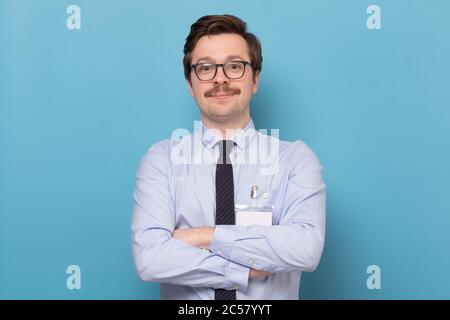 Hübscher junger Mann im Hemd, der mit gefalteten Händen auf die Kamera schaut. Stockfoto