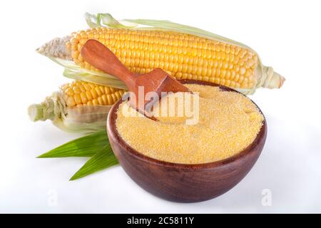 Mais mit Körnern Polenta in einer Holzschale auf weißem Hintergrund. Maisähren und -Stücke liegen neben Schalen. Glutenfreie gesunde Lebensmittel Stockfoto