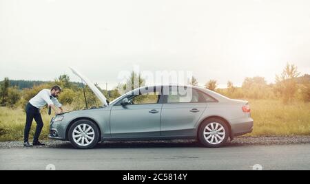 Geschäftsmann untersucht zusammengebrochene Auto Stockfoto