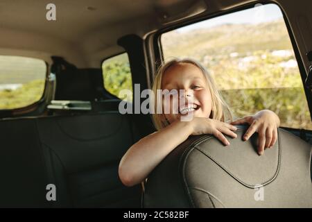 Schönes Mädchen auf dem Rücksitz des Autos sitzen. Lächelndes Mädchen, das mit einem Auto reist. Stockfoto