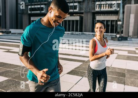 Lächelnder Mann und Frau auf einem Morgenlauf. Zwei Personen in Sportbekleidung trainieren gemeinsam in der Stadt. Stockfoto