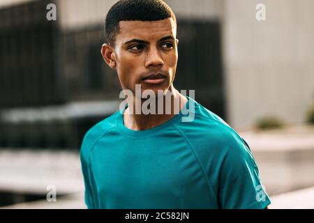 Gesunder Mann, der nach dem Training in der Stadt eine Pause einnahm. Mann in Sportbekleidung wegschauen und denken. Stockfoto