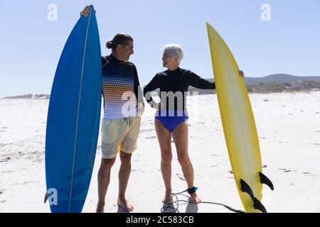 Ältere kaukasische Paar hält Surfbretter am Strand. Stockfoto