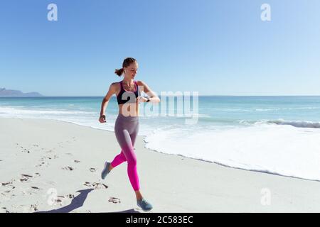 Frau, die Zeit beim Laufen am Strand überprüft Stockfoto