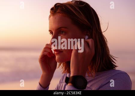 Schöne Frau mit Ohrhörern am Strand Stockfoto