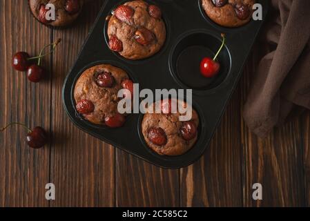 Gesunde vegane BananenkirschMuffins mit frischen Beeren auf braunem Holzhintergrund. Draufsicht. Sommeressen Stockfoto