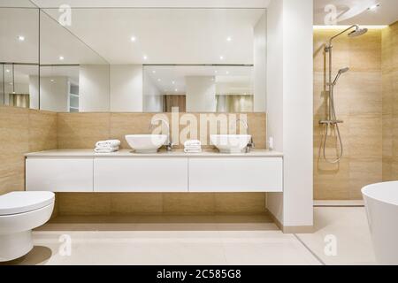 Elegante Badezimmer-Innenausstattung mit zwei weißen Waschbecken, Dusche und Badewanne Stockfoto
