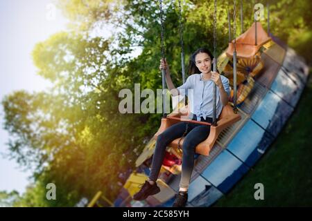 Happy Kind Teenager Mädchen Reiten Kette Karussell Schaukel im Vergnügungspark Stockfoto