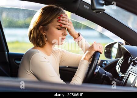 Erschöpfte Frau Fahrer Kopfschmerzen, sitzen in ihrem Auto, halten Hand an Kopf und Gefühl Angst. Stoppen Sie nach dem Autofahren im Stau.Blood Stockfoto