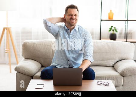 Geschäftsmann mit Nackenschmerzen nach langen Arbeitsstunden Stockfoto