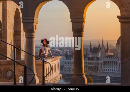 Eine glückliche junge Frau, die ihre Reise zum Schloss von Budapest in Ungarn auf dem Aussichtspunkt von Fischerbastei bei Sonnenaufgang genießt. Stockfoto