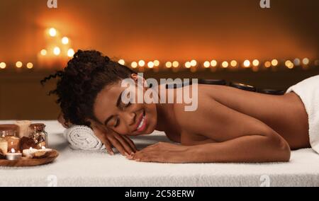 Schwarze junge Frau bekommen heiße Steine Massage Stockfoto