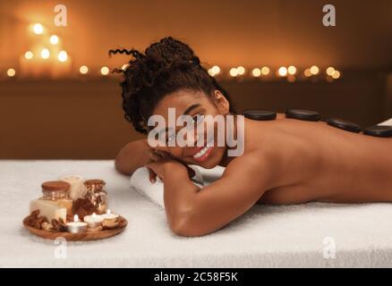 Attraktive glücklich schwarze Dame immer heiße Steine Massage Stockfoto