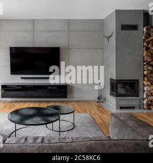 TV Wohnzimmer mit Zementwand und Kamin an der Wand montiert Stockfoto