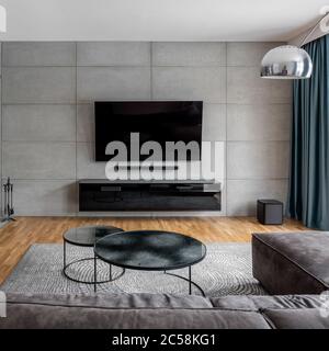 Wohnzimmer mit Zementwand und an der Wand montiertem tv Stockfoto