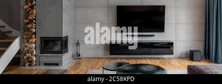 TV Wohnzimmer mit Zementwand und Wand-Kamin, Panorama Stockfoto