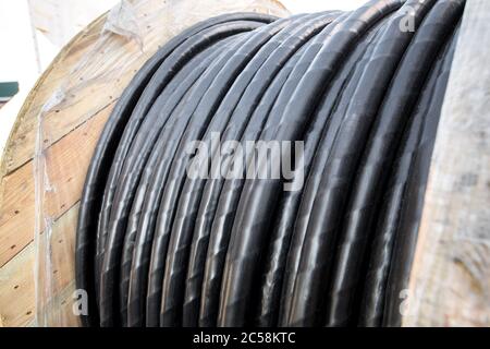 Spulen von Elektrokabel auf einer Holzrolle gewickelt, in schwarzem Gummidraht aus nächster Nähe. Stockfoto