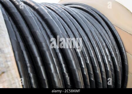 Spulen von Elektrokabel auf einer Holzrolle gewickelt, isoliert in schwarzem Gummidraht aus nächster Nähe Stockfoto