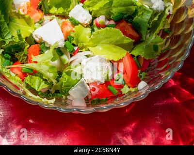 Sommersalat aus Blattsalat, Tomaten, jungen Zwiebeln, gehacktem Knoblauch, einer kleinen Menge Senfblätter und Feta-Käse, gewürzt mit Sonnenblumenöl Stockfoto