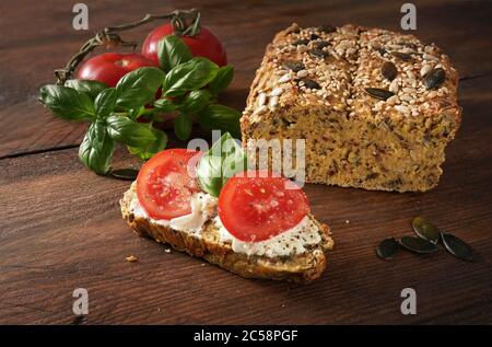 Gesundes Sandwich, hausgemachtes Proteinbrot mit Frischkäse, Tomaten und Basilikum auf einem dunklen rustikalen Holztisch, Schlankheitskur mit Low Carb oder ketogener Diät Stockfoto