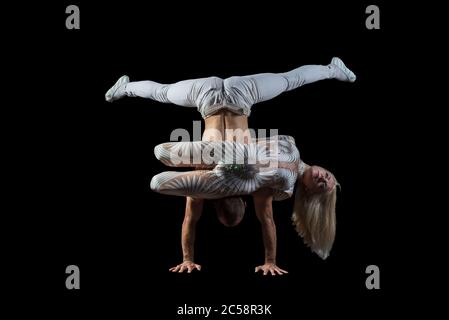 Portrait von Akrobaten Kerl mit einem Mädchen in weiß isoliert auf einem schwarzen Hintergrund. Akrobatische Fähigkeiten, Sporttanz, aktiver Lebensstil, führen Akrobaten Stockfoto