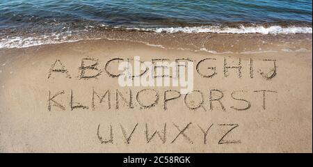 Alphabete handgeschrieben im Sand am Strand am Meer, um Ihren eigenen Text zu machen Stockfoto