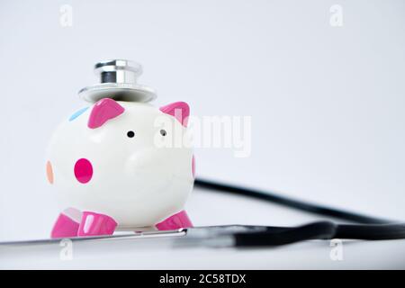 Piggy Bank und Stethoskop isoliert auf weißem Hintergrund. Finanzkonzept Stockfoto