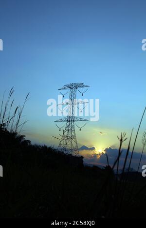 Abstrakter Natur Hintergrund. Dramatische goldene Stunde bewölkt Sonnenuntergang Himmel mit Sonnenstrahl über Hochspannungs-Strommast Stockfoto