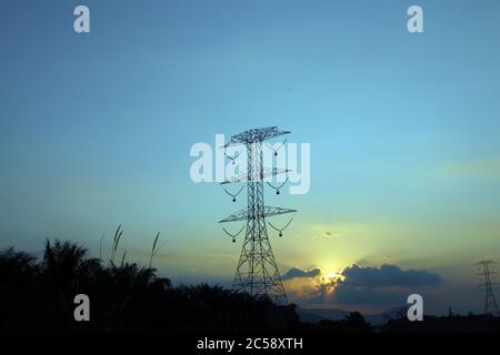 Abstrakter Natur Hintergrund. Dramatische goldene Stunde bewölkt Sonnenuntergang Himmel mit Sonnenstrahl über Hochspannungs-Strommast Stockfoto