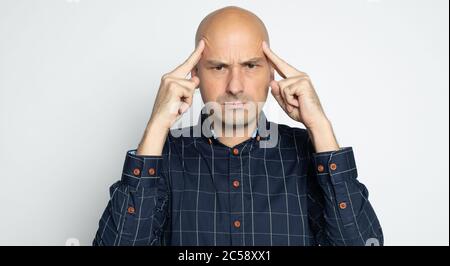 Serious Glatze Mann denkt isoliert auf grauen Studio Wand Stockfoto