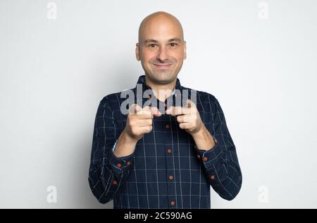 Glücklicher kahler Mann zeigt auf Sie. Isoliert auf Grau Stockfoto