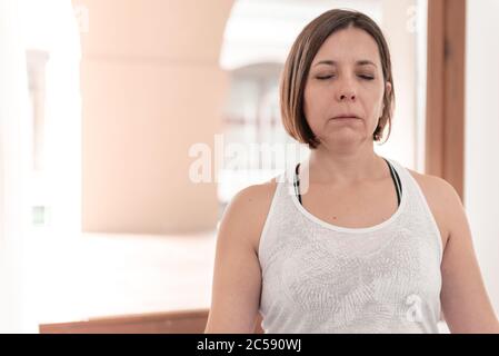 Frau, die in der Lotusposition sitzt, mit geschlossenen Augen meditiert in Stille. Yoga-Lehrer sitzt in der Lotusposition. Frau praktiziert Yoga. Stockfoto