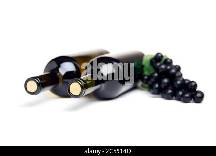 Zwei Flaschen Wein und schwarze Trauben auf weißem Hintergrund, geringe Schärfentiefe Stockfoto