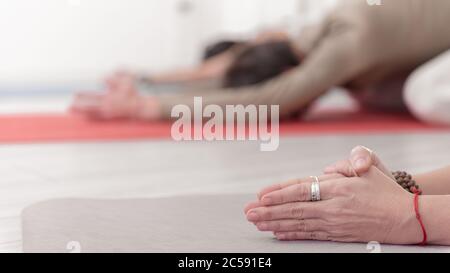 Nahaufnahme der weiblichen und männlichen Arme während der Meditation. Shashankasana Position. Hasenhaltung. Seguenz von Surya namaskar. Gruß an die Sonne. Wie Stockfoto