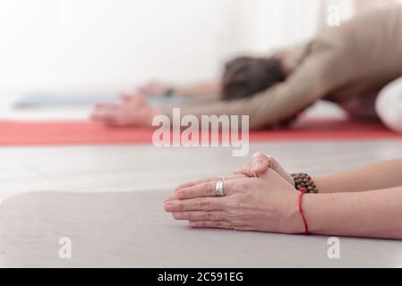 Nahaufnahme der weiblichen und männlichen Arme während der Meditation. Shashankasana Position. Hasenhaltung. Seguenz von Surya namaskar. Gruß an die Sonne. Wie Stockfoto