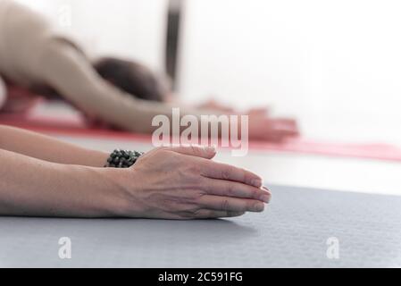 Nahaufnahme der weiblichen und männlichen Arme während der Meditation. Shashankasana Position. Hasenhaltung. Seguenz von Surya namaskar. Gruß an die Sonne. Wie Stockfoto