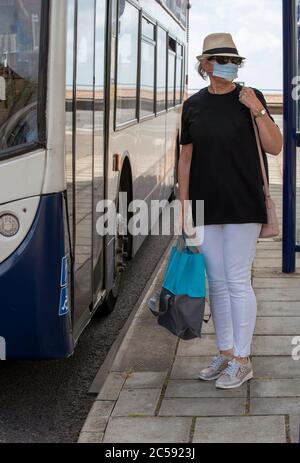 Portsmouth, England, Großbritannien, 2020. Frau mit Maske wartet während des Covid-19 Ausbruchs auf den Bus. Stockfoto