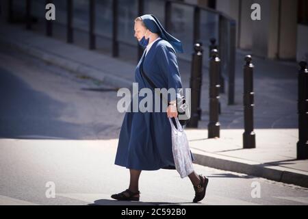 Eine Nonne, die eine Gesichtsmaske um den Hals trägt, sieht man am 1. Juli 2020 in Warschau, Polen, eine Straße überqueren. Stockfoto