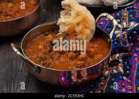 Indische Kichererbsen Garbanzo chole Masala Curry mit Naan in traditionellen Schalen Stockfoto