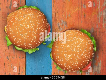 Zwei Burger auf einem farbig bemalten Holzbrett Hintergrund. Draufsicht Stockfoto