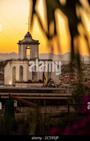 Bunte Sonnenuntergangslichter schmücken den Blick auf den Glockenturm des alten Klosters von San Antonio im historischen Stadtzentrum von San Miguel de Allende, Mexiko. Stockfoto