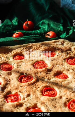 Focaccia hausgemachtes italienisches Brot gebacken mit in Scheiben geschnittenen Kirschtomaten, Meersalz und Rosmarinkräutern Stockfoto