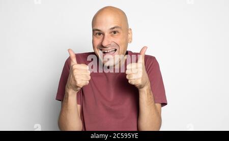 Glücklicher kahler Mann zeigt Daumen nach oben. Isoliert auf grauem Hintergrund Stockfoto