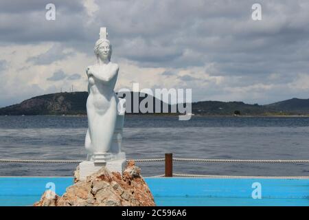 Preveza, Epirus / Greece - 05/21/2020: Meerjungfrau Skulptur in einem Brunnen im Hafen von Preveza Stadt in Griechenland. Weicher Fokus auf dem Ambracian Golf im Hintergrund Stockfoto