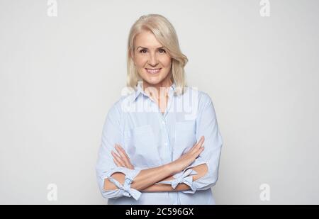 Nahaufnahme Porträt von schönen alten Erwachsenen kaukasischen blonde froh fröhlich Dame lächelnd, isoliert auf grauem Hintergrund Stockfoto