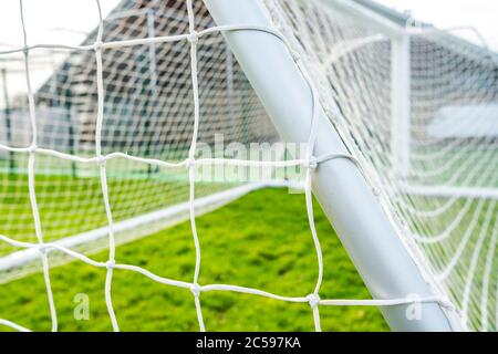 Flacher Fokus eines neu gelieferten Fußballtor in einem Dorfpark. Details des weißen Netzes und Knoten sind sichtbar. Stockfoto